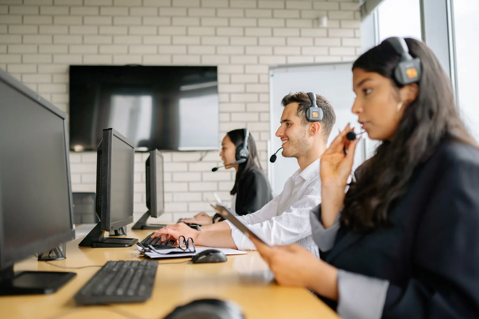 Equipe com headsets opera em estações de trabalho