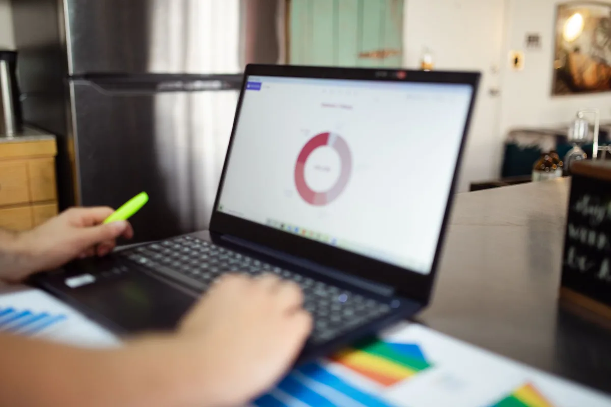 Análise de gráficos financeiros em laptop e relatórios